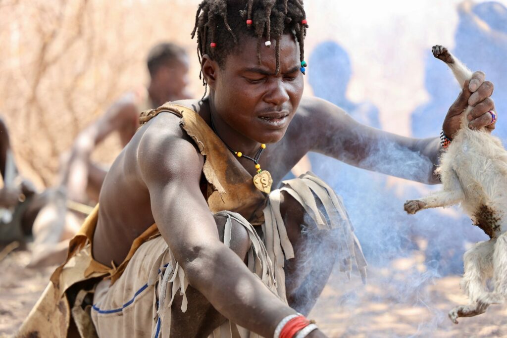 A man with dreadlocks and a dog in the background